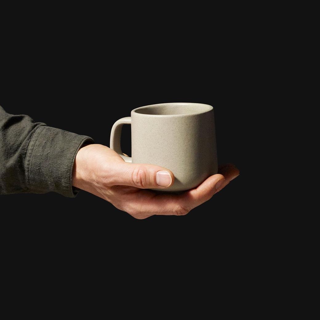 An image of a person holding a Monoware mug in pebble