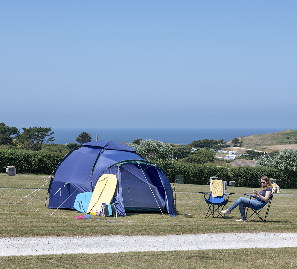 Women sat outside her tent on a camping pitch at Trevornick Holiday Park