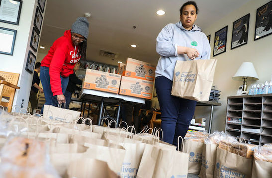 Two organizers are packing food packages for those affected by the Coronavirus pandemic.