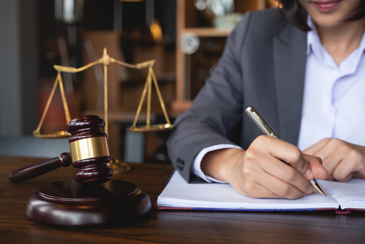 Lawyer writing in a legal pad next to a gavel and scales
