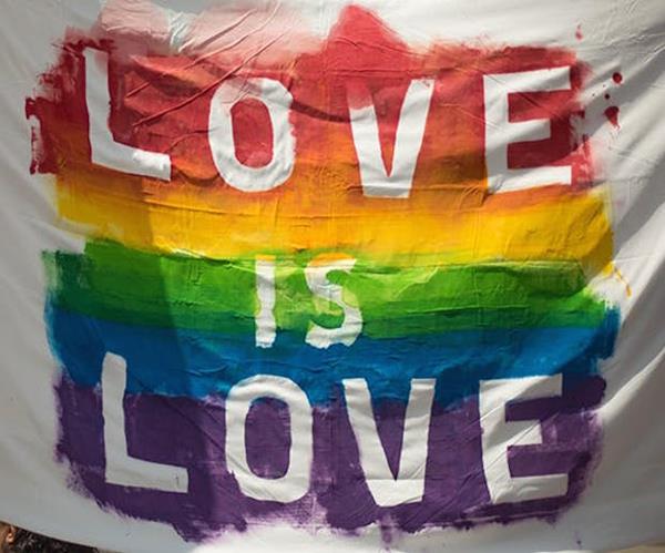 A white sheet painted with a rainbow and the words 'love is love'