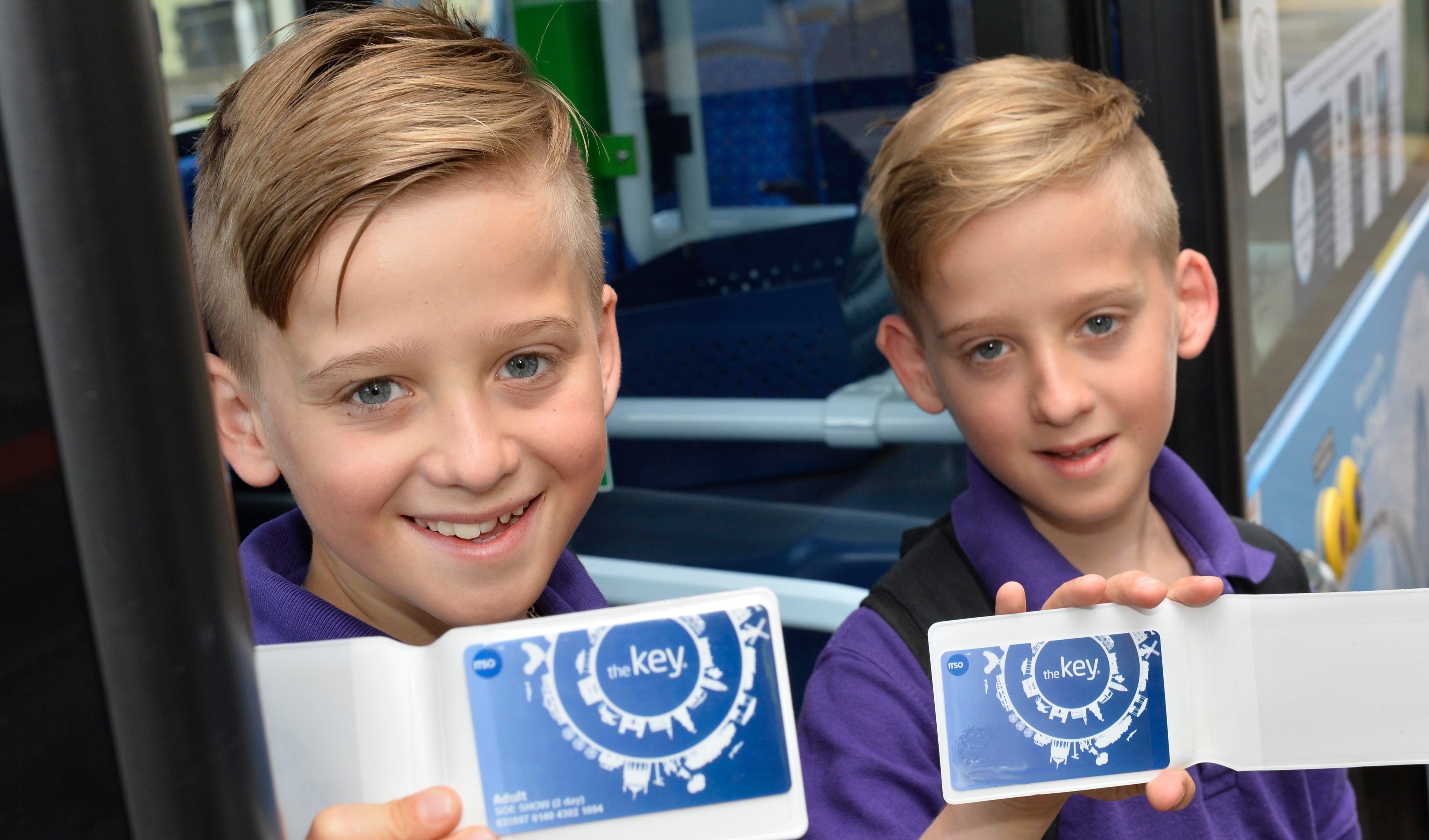two children smiling at the camera holding key cards