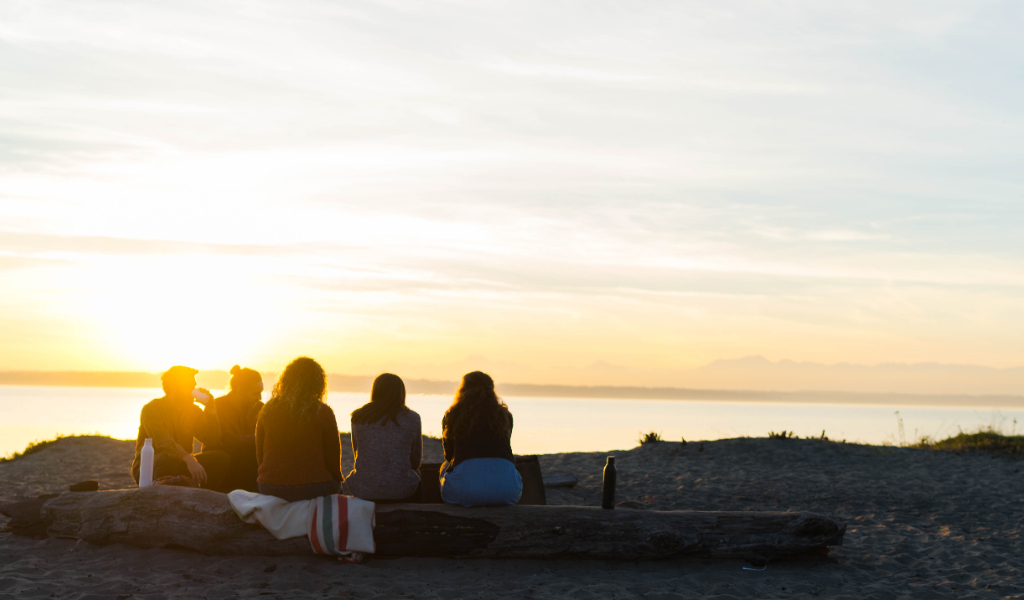 People sitting on beach watching the sunset.