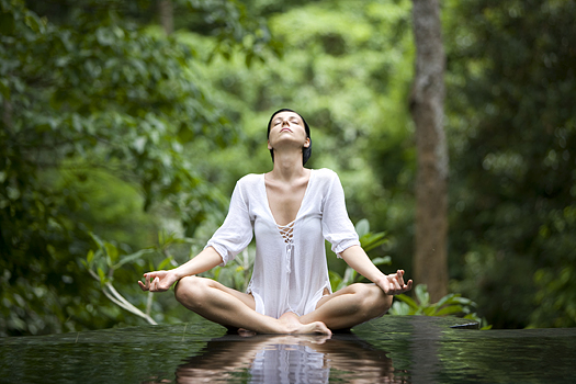 Woman in yoga pose in a pool of water in the forest