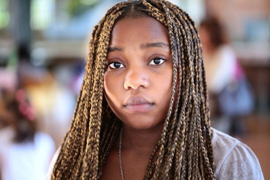 20-something year old black woman, with individual box braids staring intently into camera