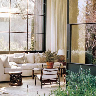 A room with a white couch, coffee table, chair and a wall of windows in the background
