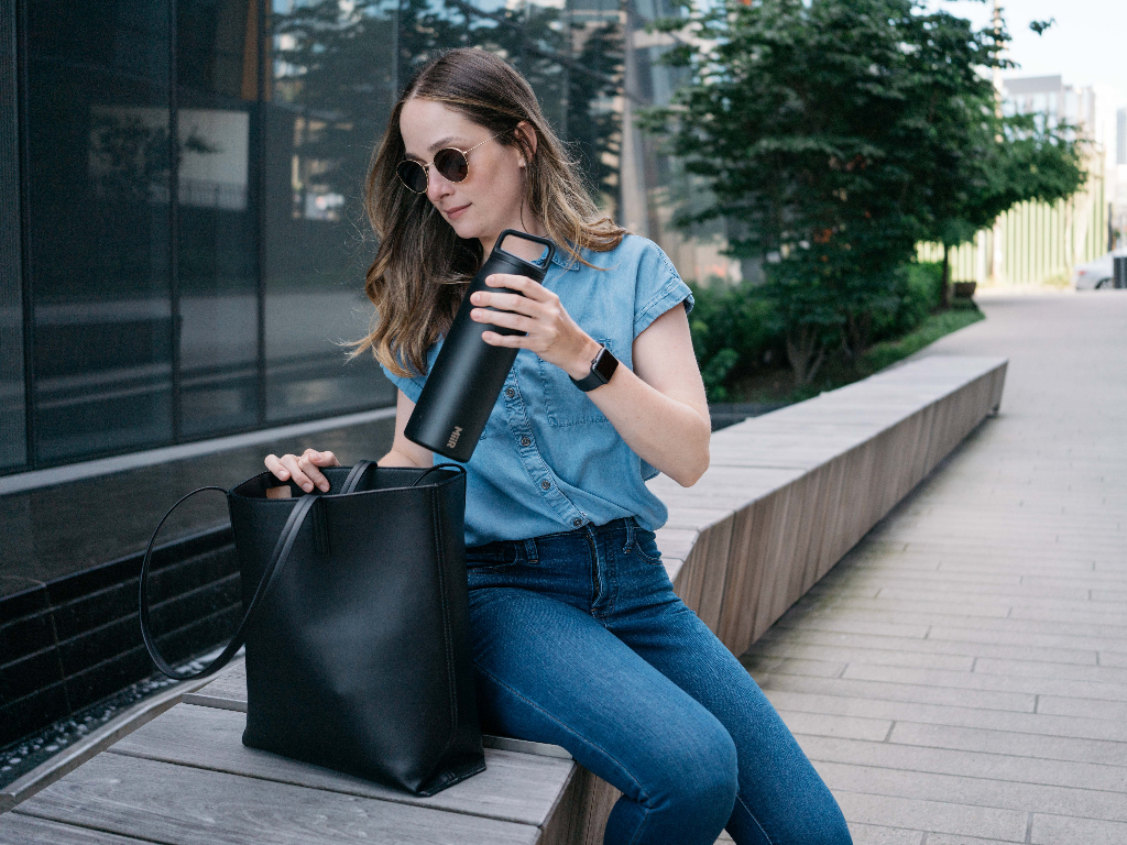 Person on bench holding 32oz Wide Mouth Bottle in Black.