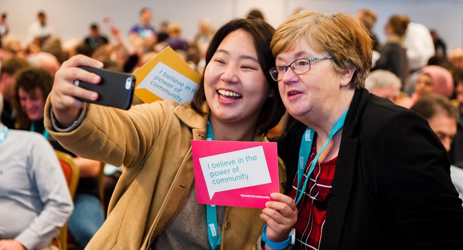 Image shows: Two people at Locality Convention '18 holding 'I believe in the power of community' sign.