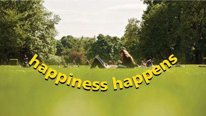 Park with people. Overlay text happiness happens