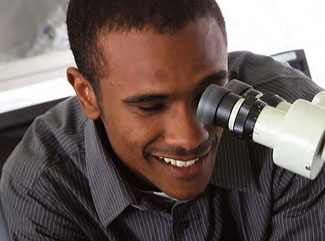 Former MSAP apprentice looking into a microscope