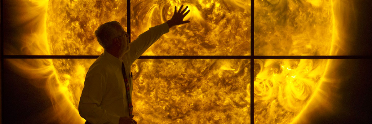 Man standing in front of large screen showing the sun.