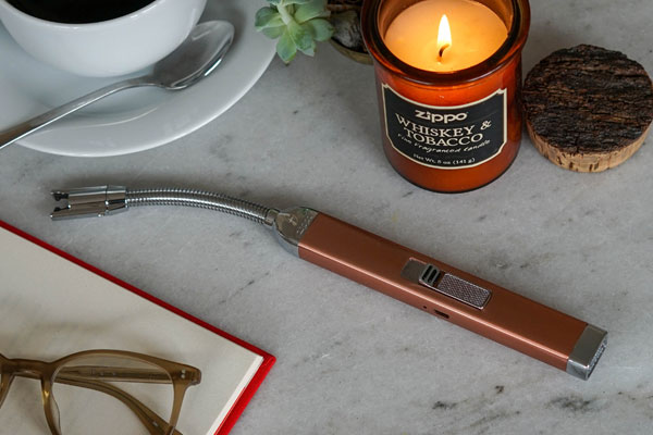 Rose Gold Rechargeable Candle Lighter on table next to lit candle