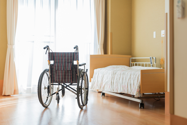 An empty bed and wheelchair at a pristine nursing home facility.