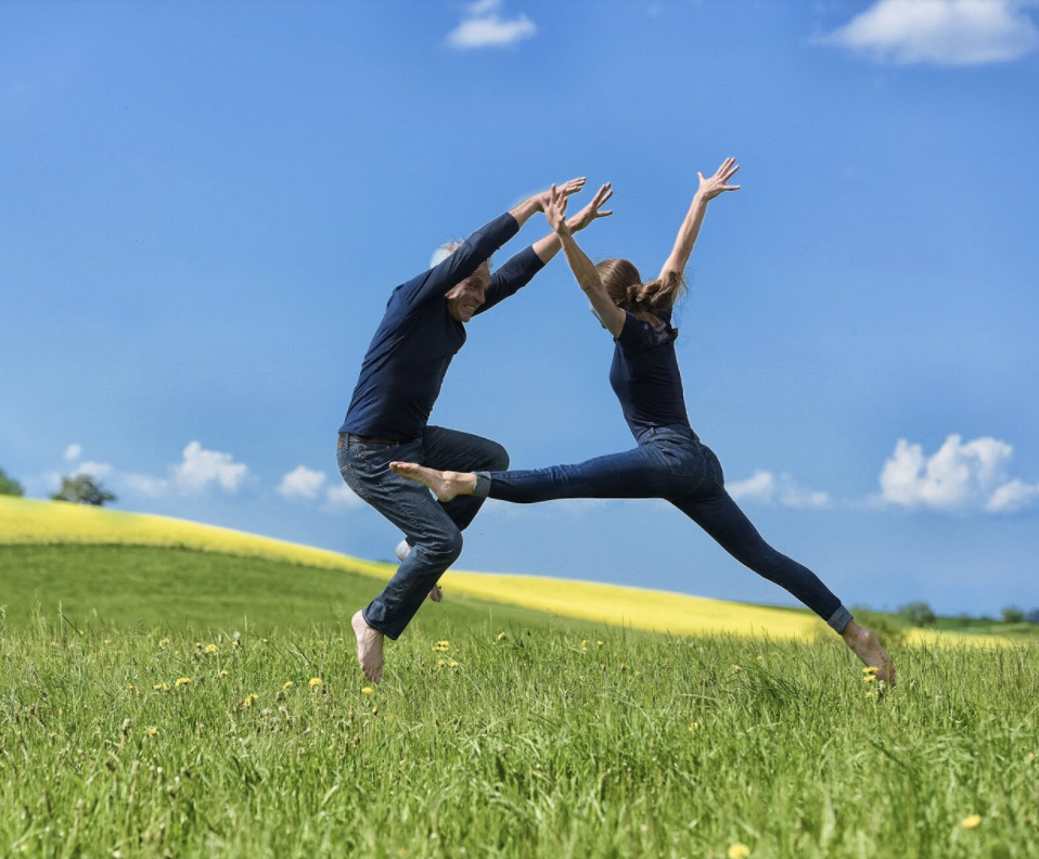 Two people jumping in grass