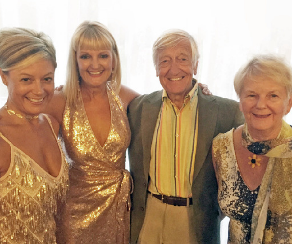 3 women and 1 man wearing gold and smiling
